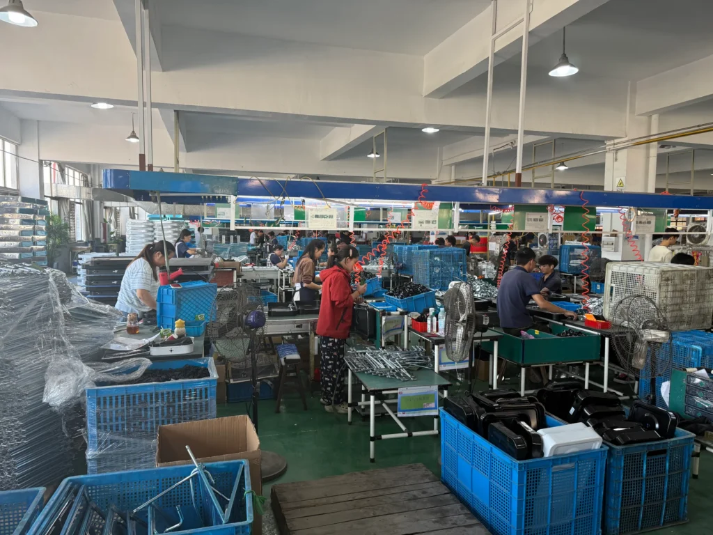 Workers assembling gas stoves on the AOFENG production line with components staged beside the workstations