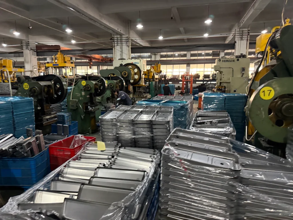 Stacks of formed stove panels beside production presses in the AOFENG factory